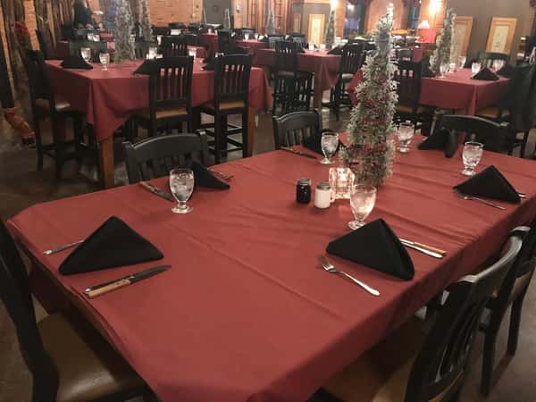 inside view of the restaurant with multiple tables and mini christmas trees on the table as centerpieces
