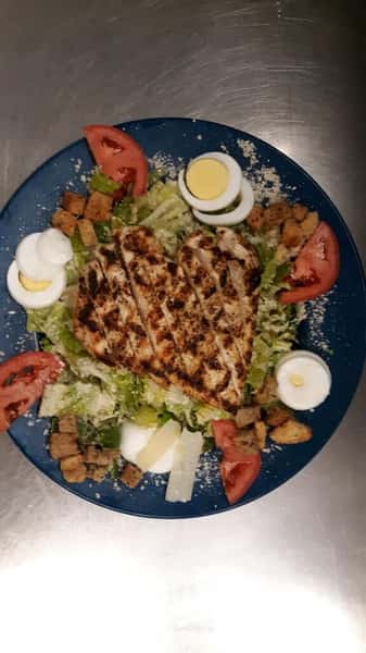a salad with tomatoes, egg, croutons, and grilled chicken on top