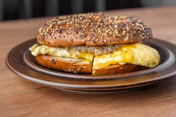 Breakfast bagel sandwich with eggs, melted cheese, and sausage on a seeded bagel, classic morning favorite