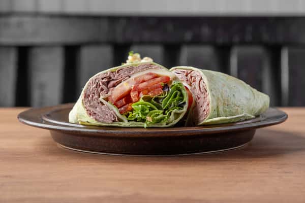 Turkey club wrap with sliced turkey, lettuce, tomato, and creamy spread, fresh deli-style sandwich