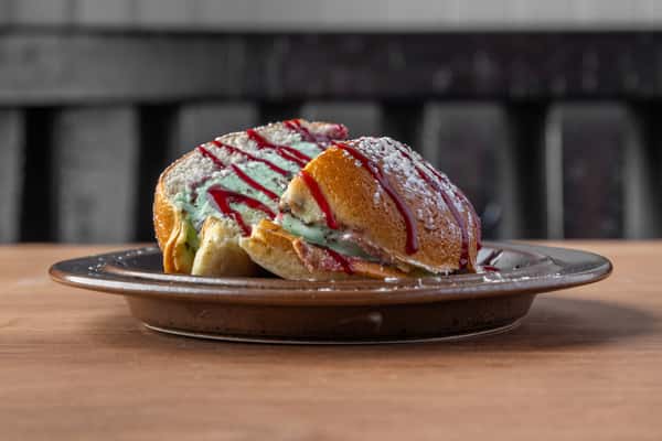 Stuffed French toast with powdered sugar and red syrup drizzle, sweet breakfast treat in a diner setting