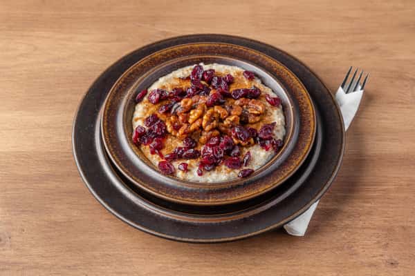Warm oatmeal topped with candied pecans, dried cranberries, and maple drizzle, hearty breakfast bowl at One Oakland