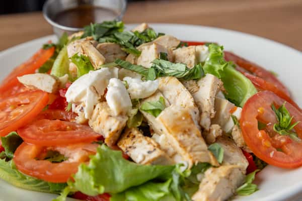 Grilled chicken salad with tomatoes, mixed greens, fresh herbs, and light dressing, healthy American lunch option