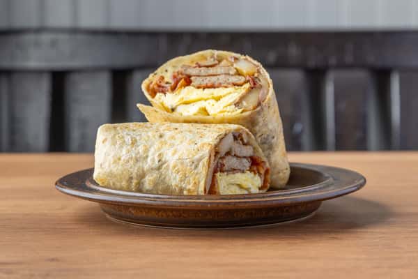 Breakfast wrap with scrambled eggs, potatoes, and bacon in a grilled tortilla, satisfying diner-style burrito