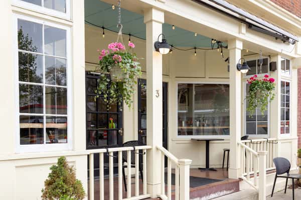 Charming restaurant exterior with covered patio, hanging flower baskets, and cozy outdoor seating at One Oakland