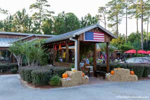 A welcoming entrance with a U.S. flag, pumpkins, and hay bales, capturing a cozy, fall atmosphere outside a restaurant.