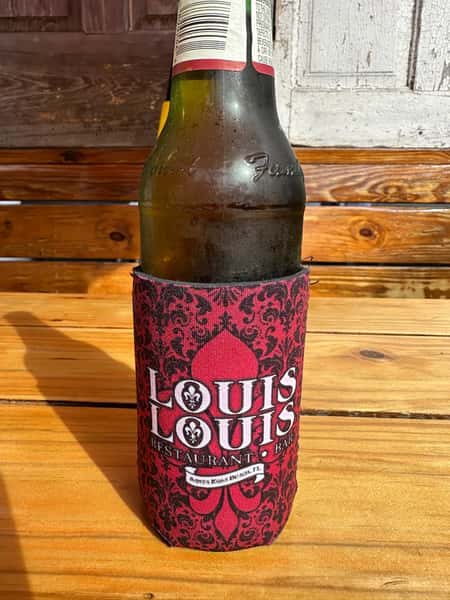 A "LOUIS LOUIS" branded bottle koozie in dark red with black damask patterns, featuring the logo and "Santa Rosa Beach, FL" text.
