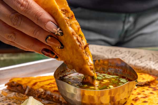 Close up of person dipping food into a sauce