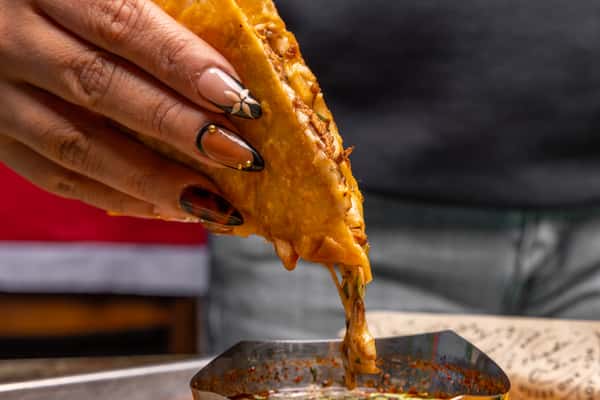 Close up of person dipping food into a sauce