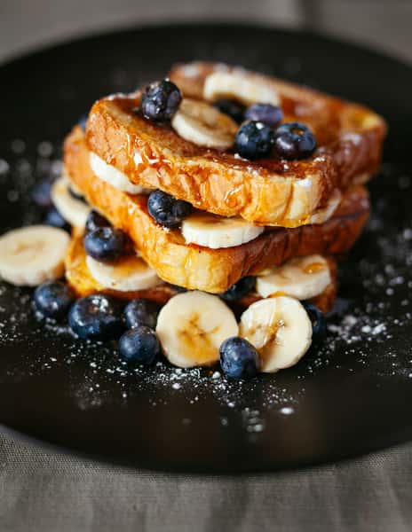 French toast with blue berries, bananas and a dusting of powder sugar