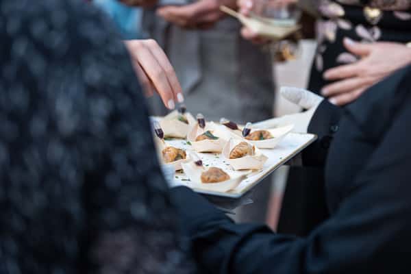 A server holding a tray of elegant appetizers at a catering event