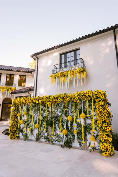 Yellow and white flowers with greenery draped across a wall and balcony