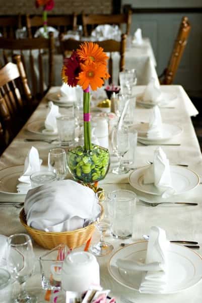 table set with glasses, utensils, and a flower with a side of bread