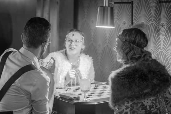 Two men and a woman playing checkers in 1920s era clothing
