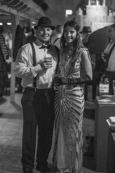 Couple dressed in flapper outfits posing for a picture