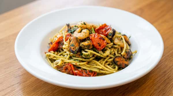 Spaghetti with shrimp, mussels, calamari, and roasted cherry tomatoes, tossed in pesto.