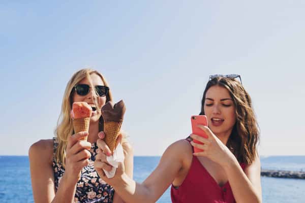 two women holding ice creams and taking a photo