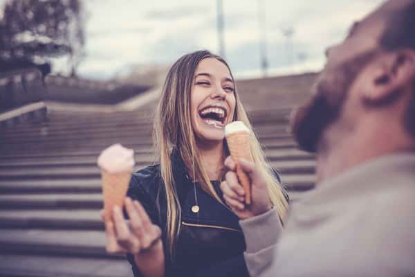 two people laughing and holding an ice cream each