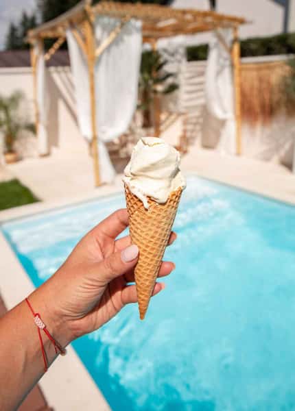 hand holding an ice cream by the pool
