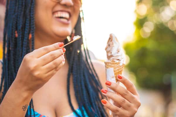 woman holding an ice cream with a spoon of ice cream on her other hand