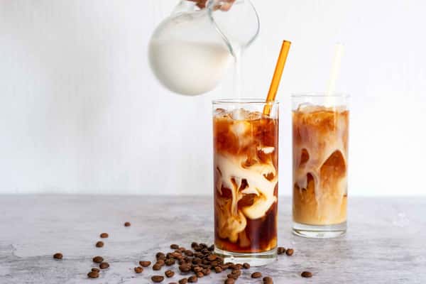 milk being poured into iced coffee