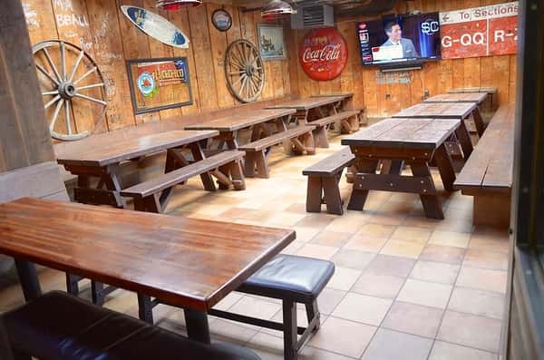 Cozy interior dining room with vintage Americana decor, wooden bench seating, and flat-screen TV, creating a nostalgic sports bar vibe ideal for casual gatherings.