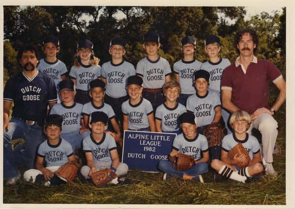 Vintage youth baseball team photo in Dutch Goose uniforms, Alpine Little League 1982, players posed outdoors with coaches.