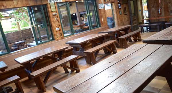 Rustic indoor dining area with long wooden picnic tables and benches, offering a casual, communal atmosphere perfect for groups at this classic American eatery.