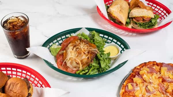ettuce-wrapped burger topped with grilled onions, tomatoes, and a side of yellow dipping sauce, paired with a fizzy cola and surrounded by a sub sandwich, mini burgers, and a Hawaiian pizza — ideal for a casual American eatery menu.