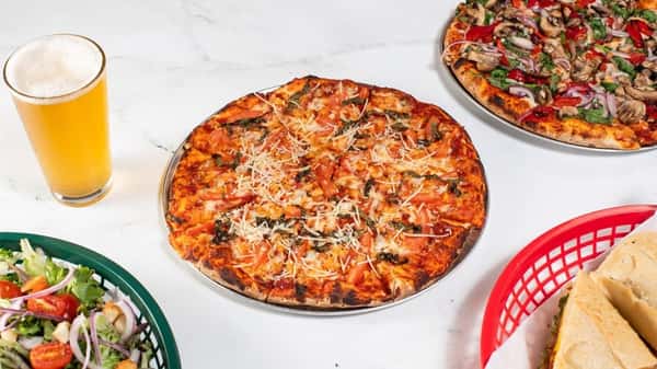 Thin-crust pizza topped with tomato slices, fresh basil, and shredded Parmesan, paired with a golden pint of beer — a simple yet flavorful Italian-inspired dish perfect for casual dining.