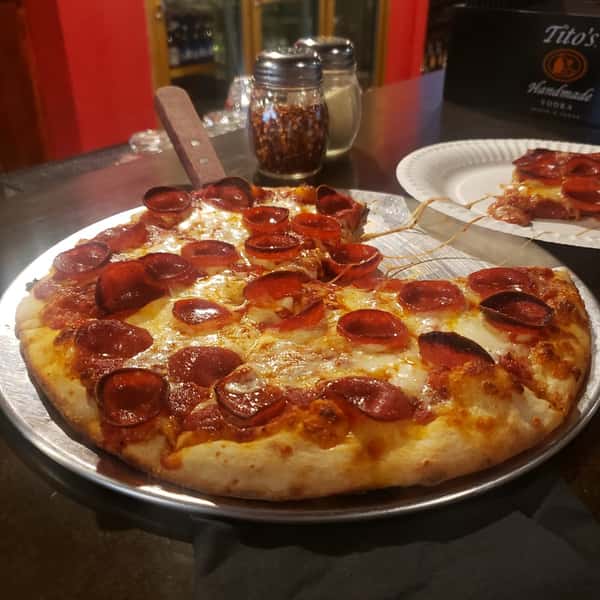 Freshly baked pepperoni pizza with bubbly cheese and thick crust on a round tray at a local pizza pub.