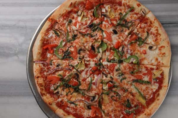 Vegetarian pizza topped with green bell peppers, red onions, mushrooms, diced tomatoes, and fresh herbs over melted mozzarella and zesty tomato sauce on a hand-tossed crust – colorful veggie pizza perfect for a casual Italian pizzeria menu.