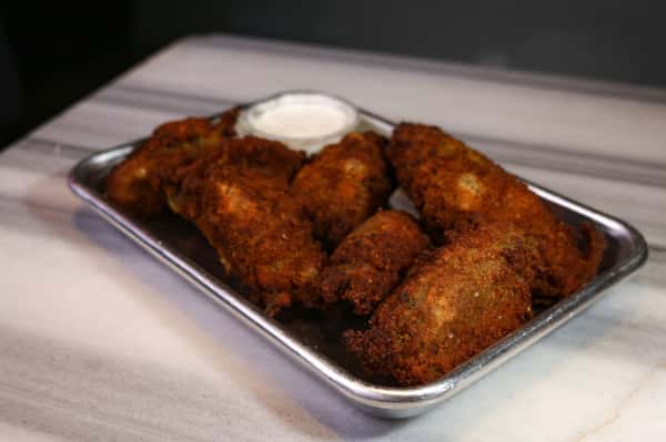 Basket of crispy fried chicken wings served with ranch dipping sauce at a lively pizza and sports bar.