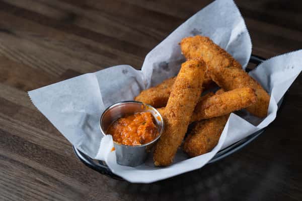 Crispy mozzarella sticks served in a basket with marinara dipping sauce – golden fried cheese appetizer perfect for a casual Italian restaurant or sports bar menu.