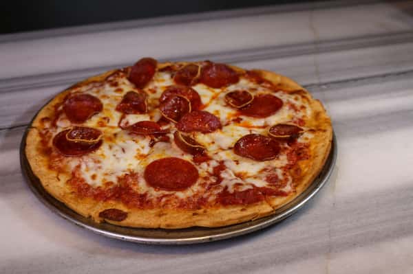 Freshly baked pepperoni pizza with bubbly cheese and thick crust on a round tray at a local pizza pub.