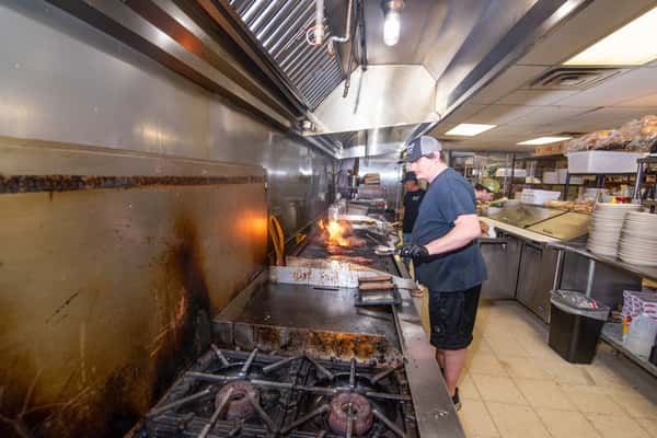 Open kitchen with chefs cooking on the line at Blackwell Revival in Atkins, Arkansas, highlighting a lively restaurant experience