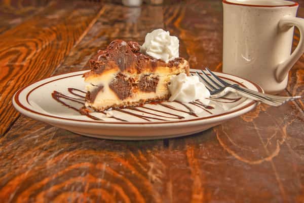 Slice of cheesecake drizzled with chocolate sauce and topped with whipped cream at Blackwell Revival in Atkins, AR