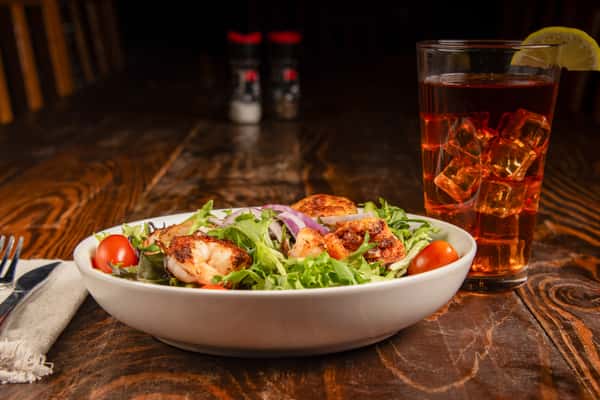 Mixed greens salad topped with grilled shrimp, tomatoes, and croutons at Blackwell Revival in Atkins, AR, blending fresh and Cajun flavors