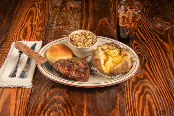 Angled view of 8 oz sirloin steak with baked potato, roll, and sides at Blackwell Revival in Atkins, AR