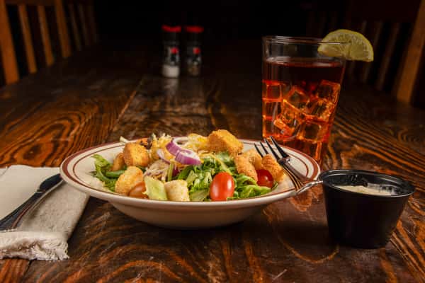 Fresh side salad with crisp greens, tomatoes, croutons, and dressing at Blackwell Revival in Atkins, Arkansas