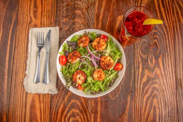 Overhead view of mixed greens salad with grilled shrimp, tomatoes, and red onions at Blackwell Revival in Atkins, Arkansas