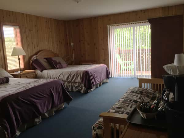 Motel bedroom showing couch, two beds and sliding door out to balcony