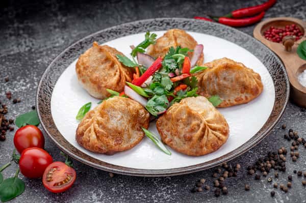Pan-fried dumplings topped with fresh herbs at Laghman Express