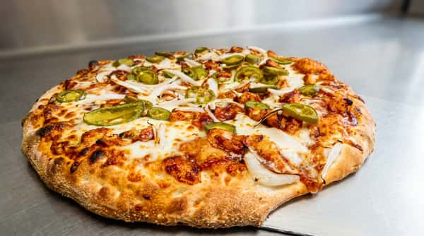 BBQ chicken pizza with melted cheese, sliced onions, and jalapeños on a golden-brown crust.