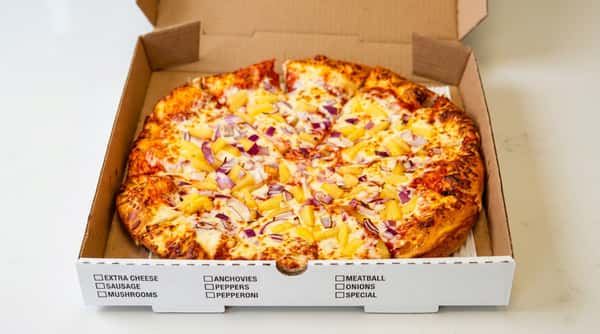 Pizza with pineapple and red onion toppings in a cardboard delivery box, held by hands.