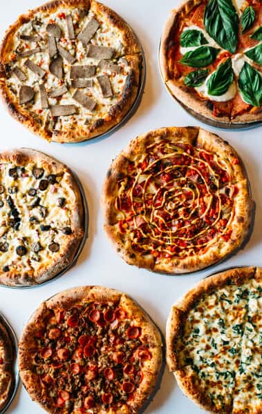 A variety of different flavored pizzas on a table