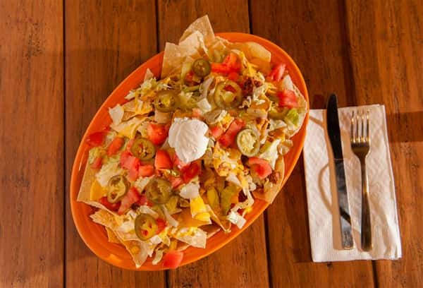big bowl of tortilla chips covered in dip and sour cream