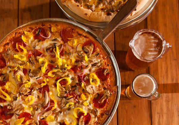 supreme pizza with a pitcher of beer
