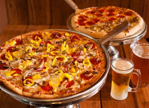 two pizzas, one supreme, one pepperoni with a glass of beer