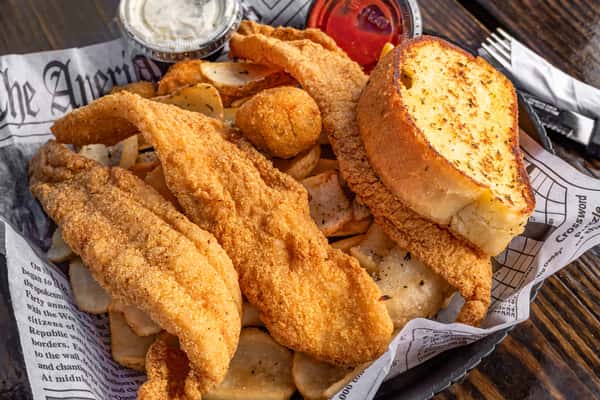 Southern-style fried catfish fillets with seasoned potato wedges, hushpuppies, garlic bread, tartar sauce, and ketchup.